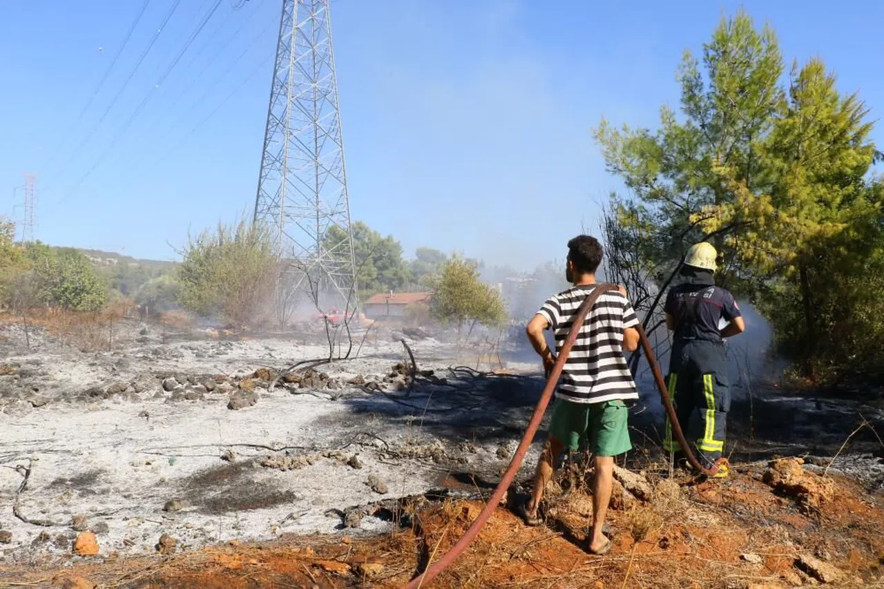 Evinin etrafını saran alevlere gözyaşları içinde hortumla müdahale etti